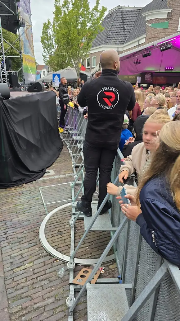Beveiliger van Reaction Security houdt overzicht bij de hekken voor een podium